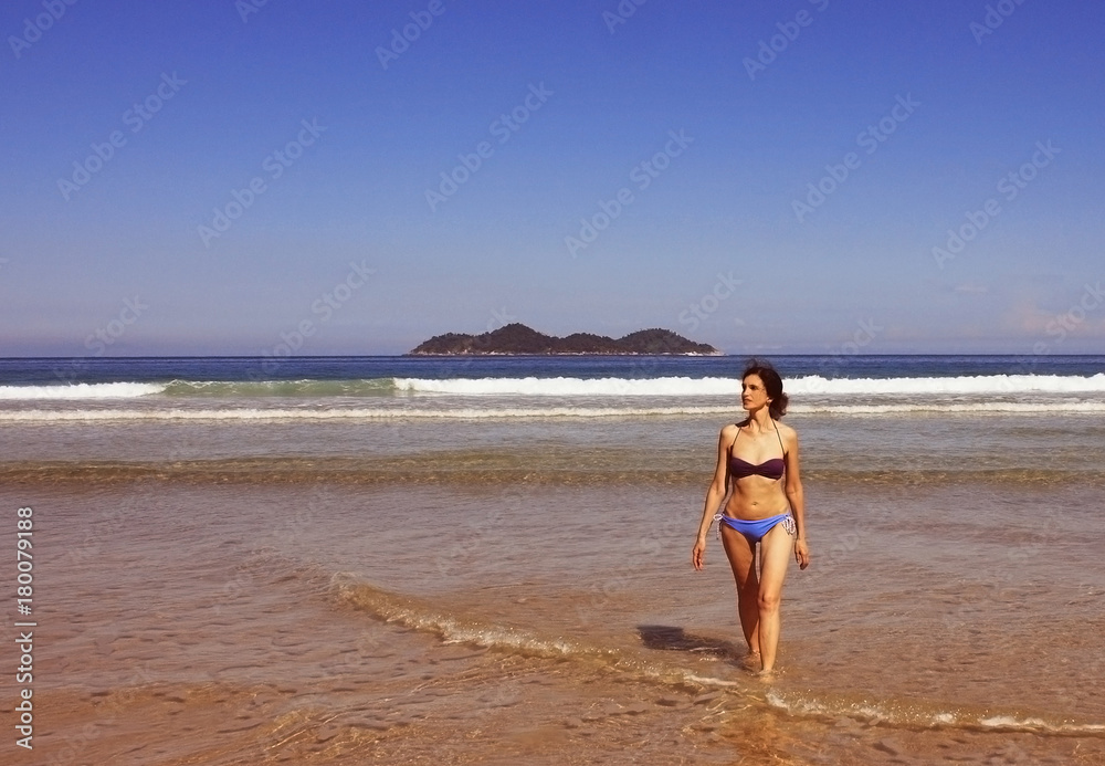 mid age woman in swimsuit walking on beach, Brazil