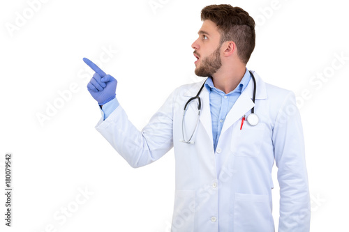 Portrait of a Young smiling male doctor pointing finger away isolated on a white background
