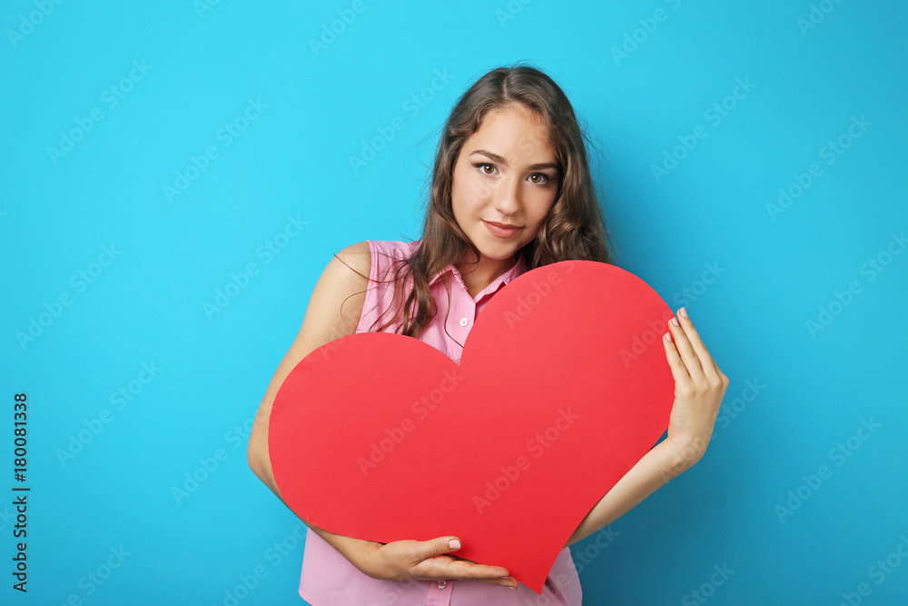 Portrait of young woman holding red heart on blue background Portrait of young woman holding red heart on blue background