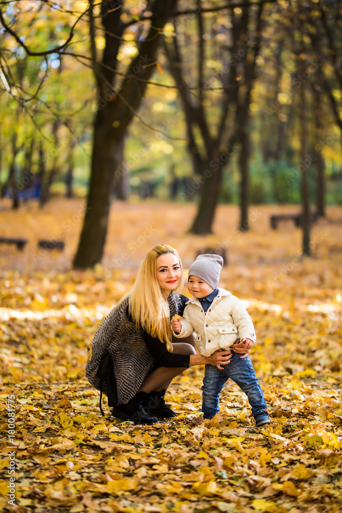 Fototapeta premium Happy family having fun outdoors in autumn park against yellow leaves background