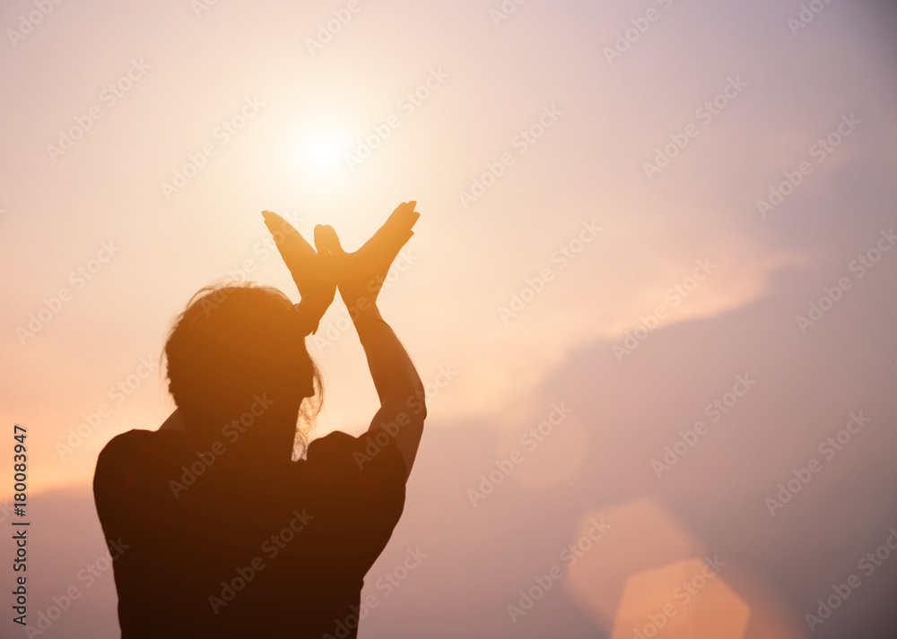 Silhouette of woman praying over beautiful sky background