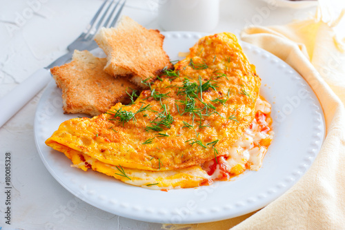 Scrambled eggs with tomatoes and cheese on a white plate, the idea of a morning breakfast, horizontal