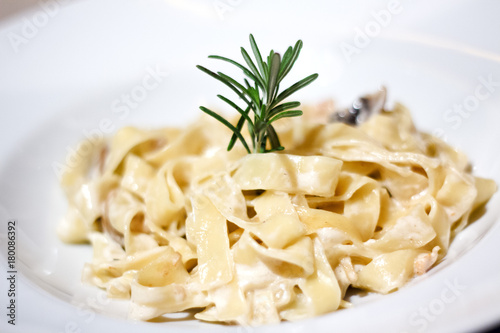 Pasta with creamy sauce in white bowl with chicken decorated thyme. .