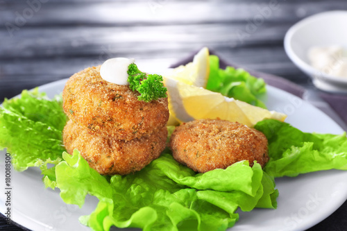 Plate with tasty salmon patties on table, closeup