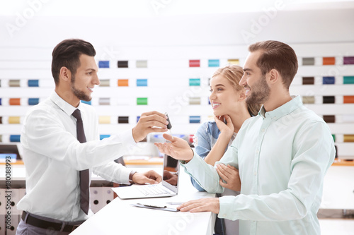 Car salesman giving key to couple in dealership