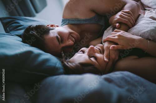 Happy couple cuddling in cozy bed in morning