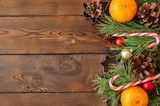 Christmas decoration. Background with fir tree branches, oranges, candy canes and cookie cutters. Wooden backdrop.