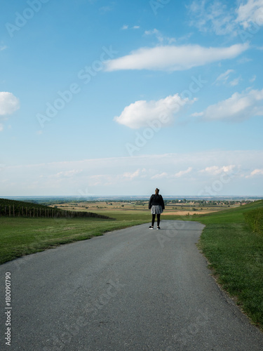 Young woman walking on the road close to the vineyard