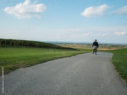 Woman walking on the road close to the vineyards © MaZvone