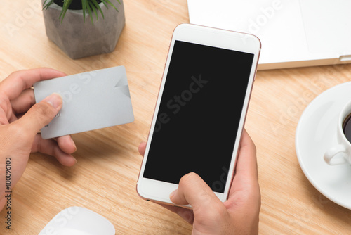 Businessman holding hand credit card and using smartphone.