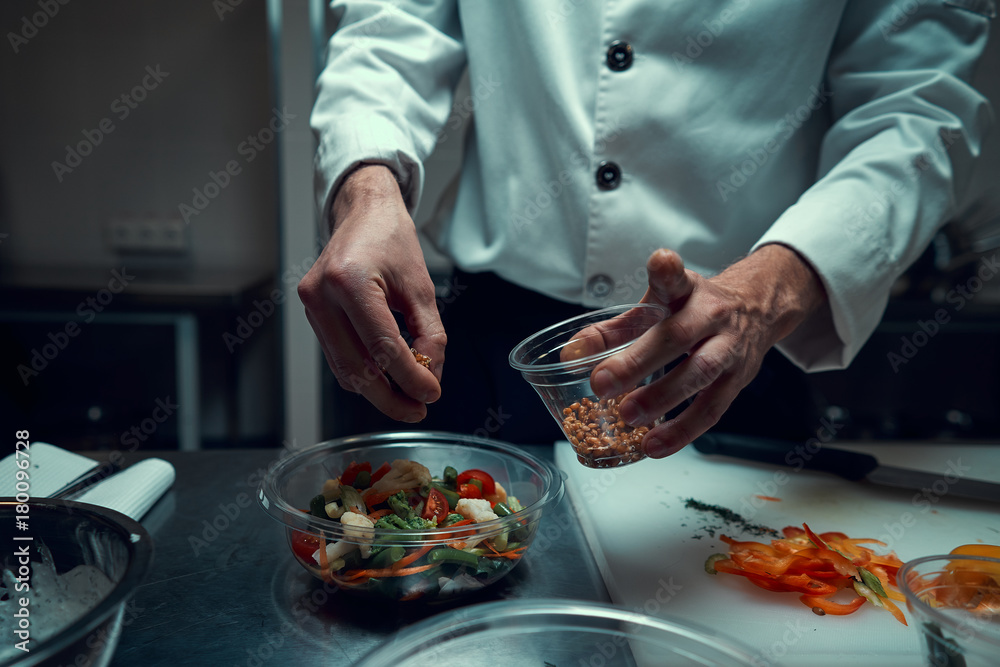 The chef prepares the dish. Sprinkle the salad with spices. Cooking. Professional kitchen. Salad dressing. Spices for salad