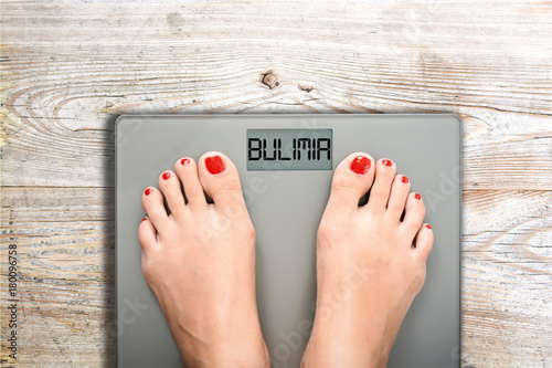 Health and care concept with bulimia word on bathroom scale while a woman is weighting photo