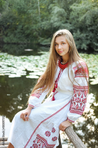 Beautiful slavonic girl with long blond hair and blue eyes sitting near river