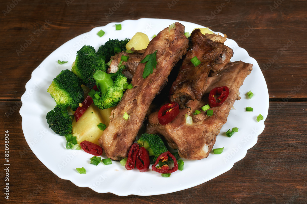 roasted pork ribs with potatoes and broccoli on an old wooden table roasted pork ribs with potatoes and broccoli on an old wooden table