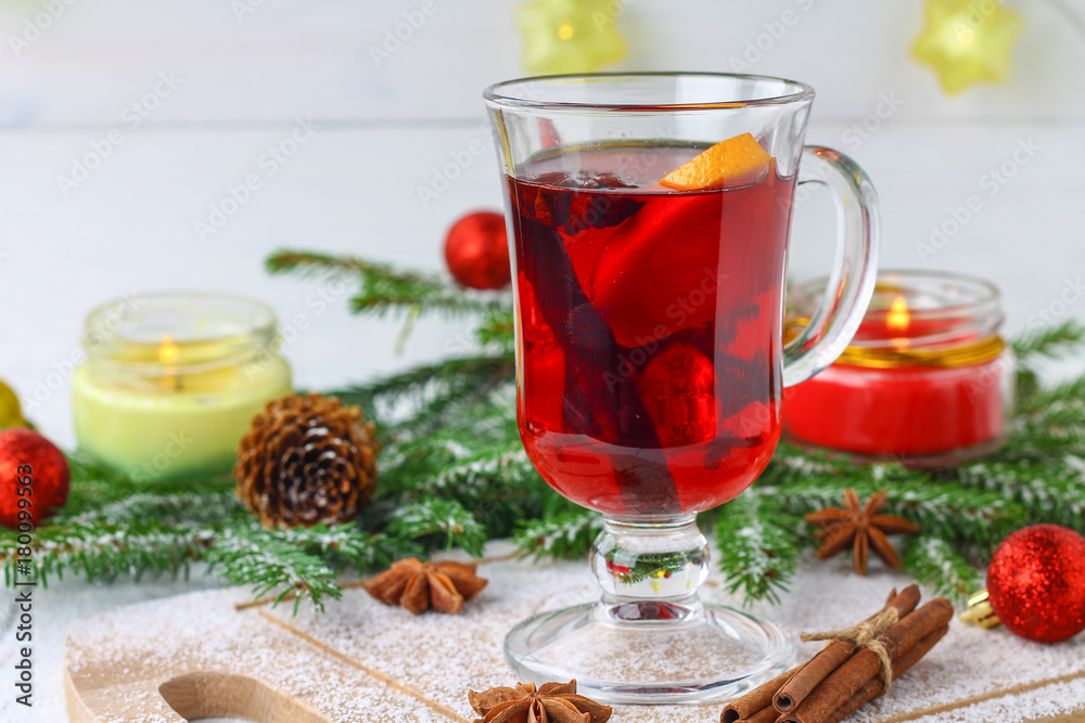 New Year's mulled wine in a glass on the background of twigs, candles and garlands. New Year's mulled wine in a glass on the background of twigs, candles and garlands.