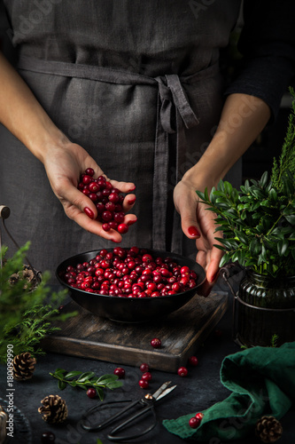 Принти на полотні fresh cranberry in woman hands. Dark kitchen table