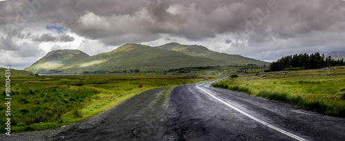 Road in Connemara national park Ireland with stormy clouds