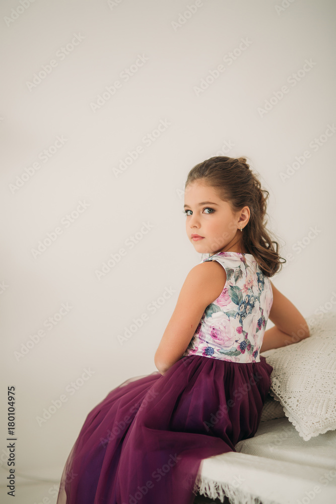 Beautiful girl in a purple dress and flower blouse posing for a photographer. Beautiful girl in a purple dress and flower blouse posing for a photographer.