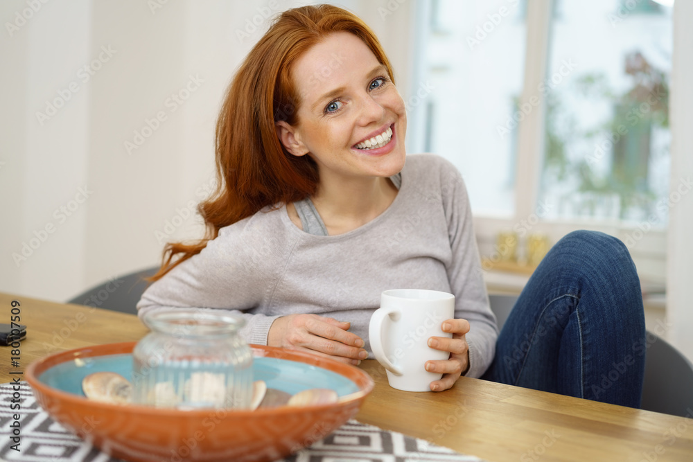 frau sitzt zuhause am tisch mit einer tasse tee frau sitzt zuhause am tisch mit einer tasse tee