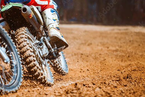 Close-up part of mountain bikes race in dirt track with flying debris during an acceleration in sunshine day time. Concept of focus between an accelerate in action sport