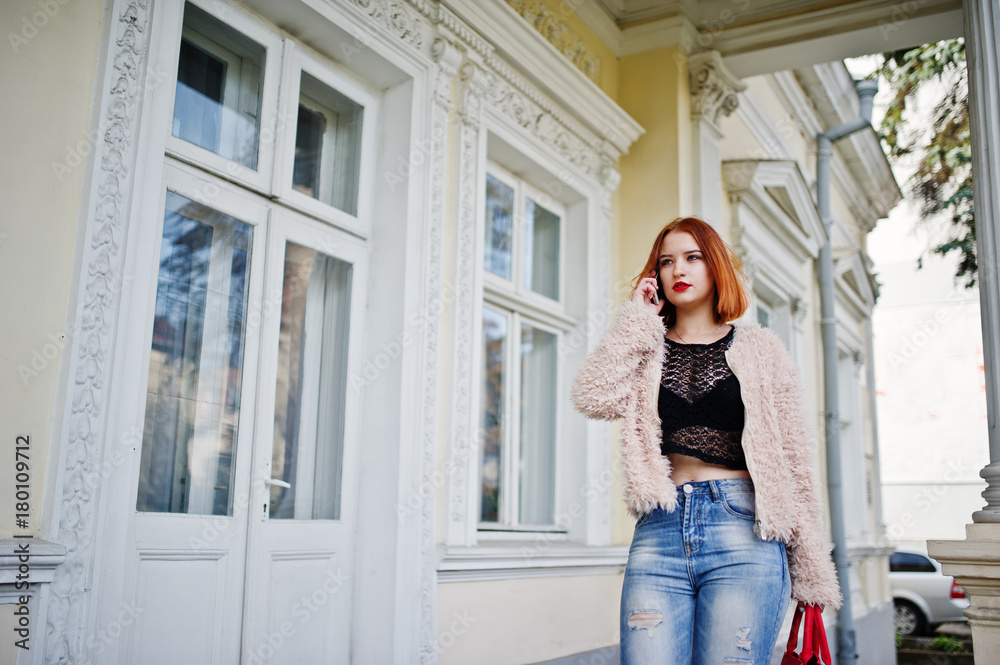 Red haired girl with red handbag posed near vintage house and speaking on mobile phone. Red haired girl with red handbag posed near vintage house and speaking on mobile phone.