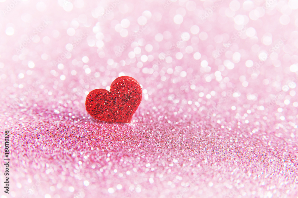 Valentines bright red heart on a pink glitter background.