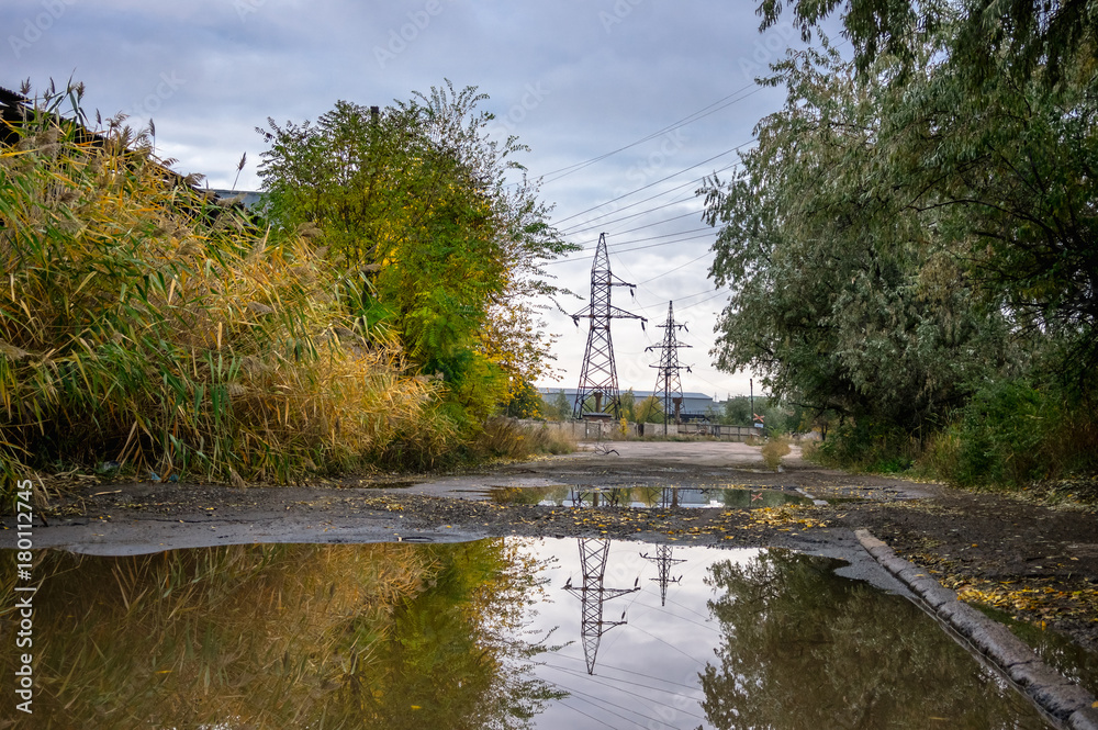 Old road with puddles in the industrial area in autumn.