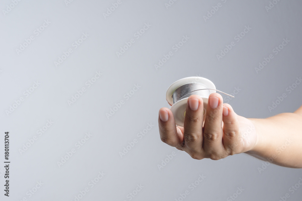 Hand holding solder wire roll for soldering in electronic equipment Hand holding solder wire roll for soldering in electronic equipment