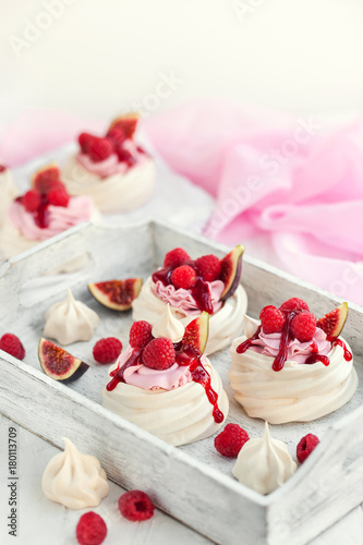 Delicious mini Pavlova meringue cake decorated with fresh raspberry, figs and berry sauce