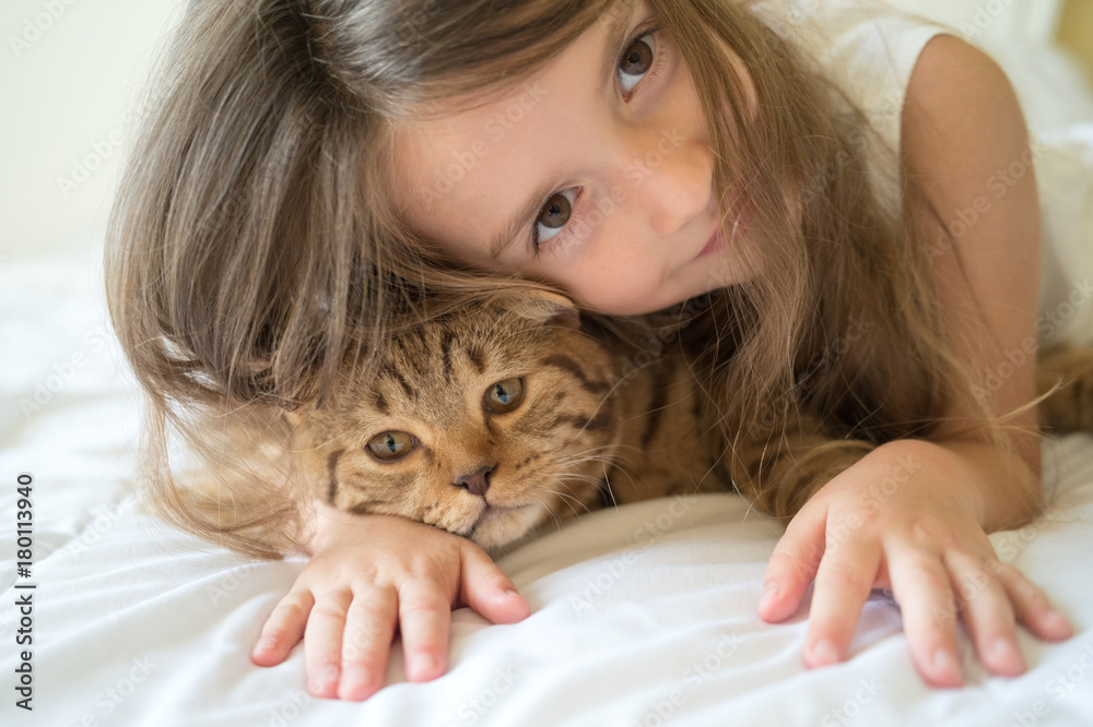 Child playing with cat on bed Child playing with cat on bed