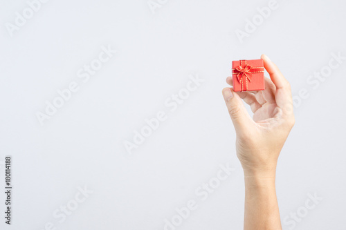 Hand holding small red gift box with ribbon and bow for special photo