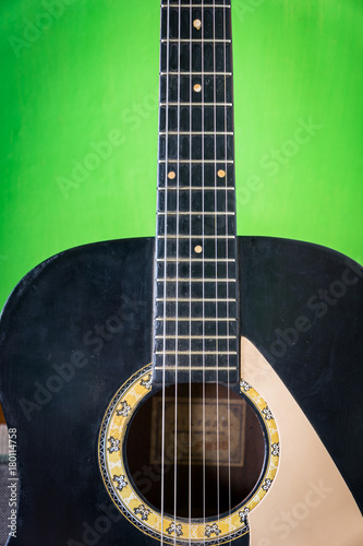 old acoustic guitar on green paint wall background - vintage grunge style