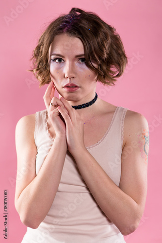 Portrait of young woman in shirt and choker. Holding arms close to face.