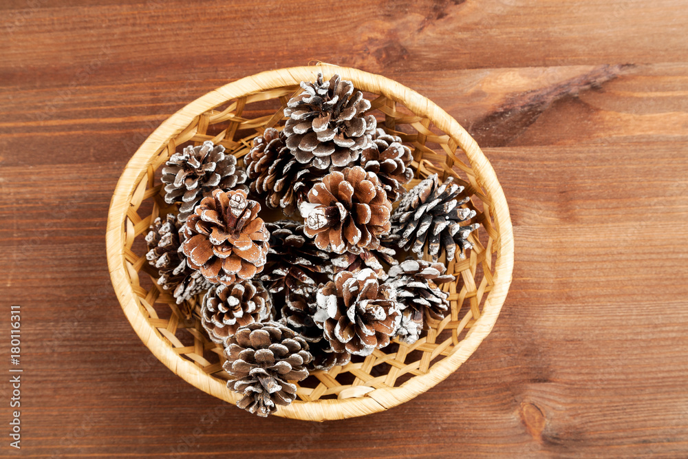 Dry fir tree cones in a wicker basket on a wooden table Dry fir tree cones in a wicker basket on a wooden table