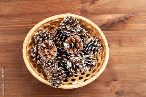 Dry fir tree cones in a wicker basket on a wooden table