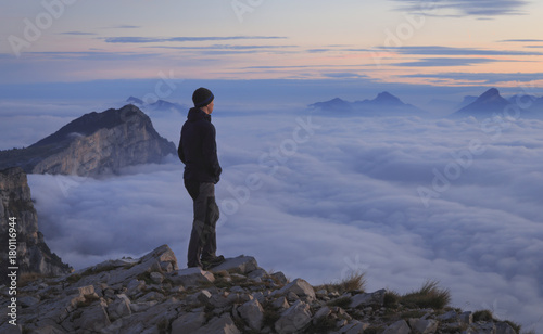 A hiker looking over a sea of clouds in the mountains at dawn.