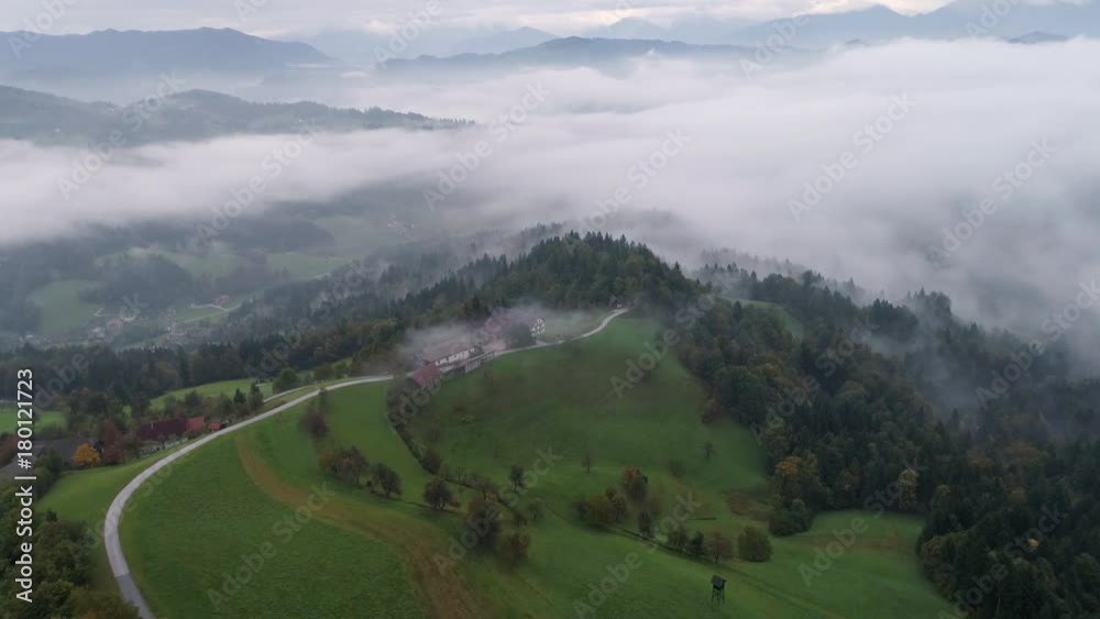 Aerial view of road leading towards farmhouse in foggy forest landscape in Skofja Loka Slovenia. Aerial view of road leading towards farmhouse in foggy forest landscape in Skofja Loka Slovenia.