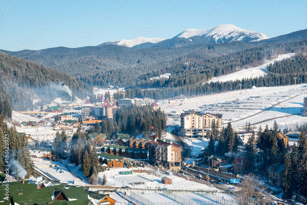 Beautiful view of a ski resort Bukovel in the Carpathians mountains in the morning. Blue sky, mountains, forests on the background. Ski season and winter sports concept