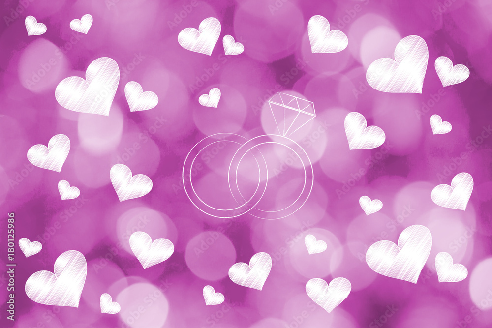 wedding rings surrounded by lovehearts on pink bokeh background