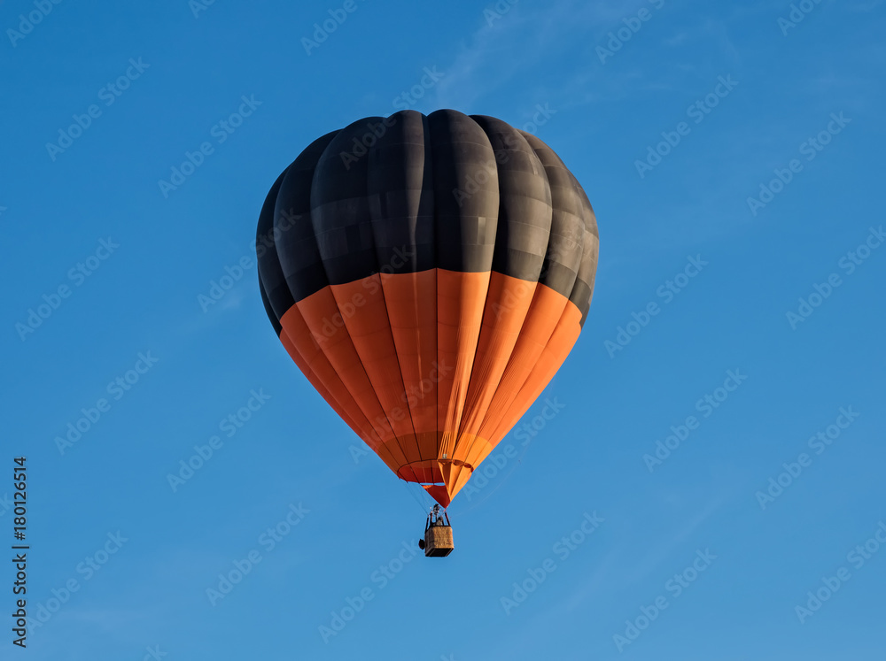 Fototapeta premium globo aerostático naranja y negro sobre cielo azul