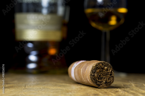 Close-up photo of still life with a cigar, a bottle of alcohol and a glass of whiskey on an old wooden table