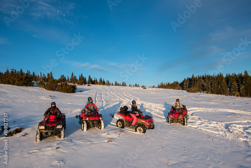 Group of people sitting on off-road quad bikes in the the mountains in winter evening photo