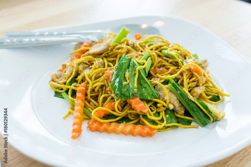 Fried yellow noodles with pork in white dish