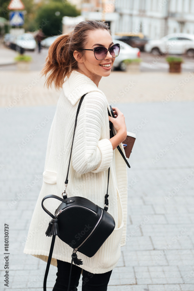 Young happy lady walking outdoors drinking coffee. Young happy lady walking outdoors drinking coffee.