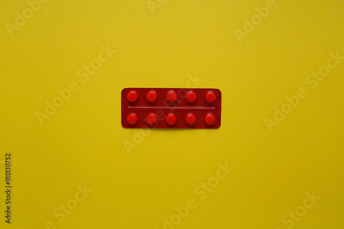 Obraz na płótnie Tablets in a blistered red package on a yellow background from above
