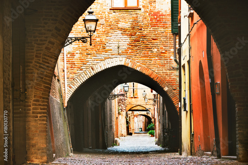 Ferrara, Italy - 22.06.2017: The streets of the historic Italian city of Ferrara, typical Italian narrow streets and with arches, ancient lanterns photo