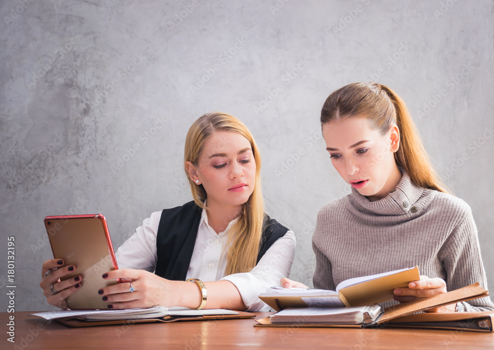 Two young european business women are sitting on the table and discussing about their work or project Two young european business women are sitting on the table and discussing about their work or project