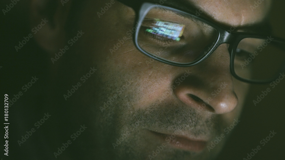 Gambling addicted man with glasses in front of online casino slot machine on laptop computer at night - loosing his money. Dramatic low light grain shot. Gambling addicted man with glasses in front of online casino slot machine on laptop computer at night - loosing his money. Dramatic low light grain shot.