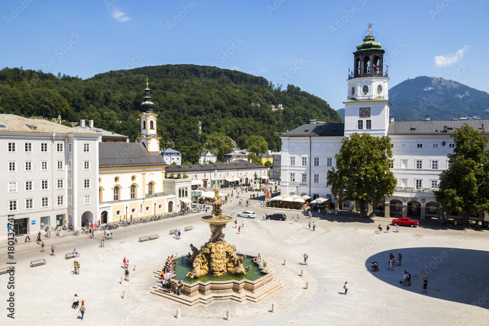 Fototapeta premium Residenzplatz w Salzburgu w Austrii z kościołem św. Michała (Michaelskirche), fontanną Residenzbrunnen i nową rezydencją (Neue Residenz) z widoczną dzwonnicą