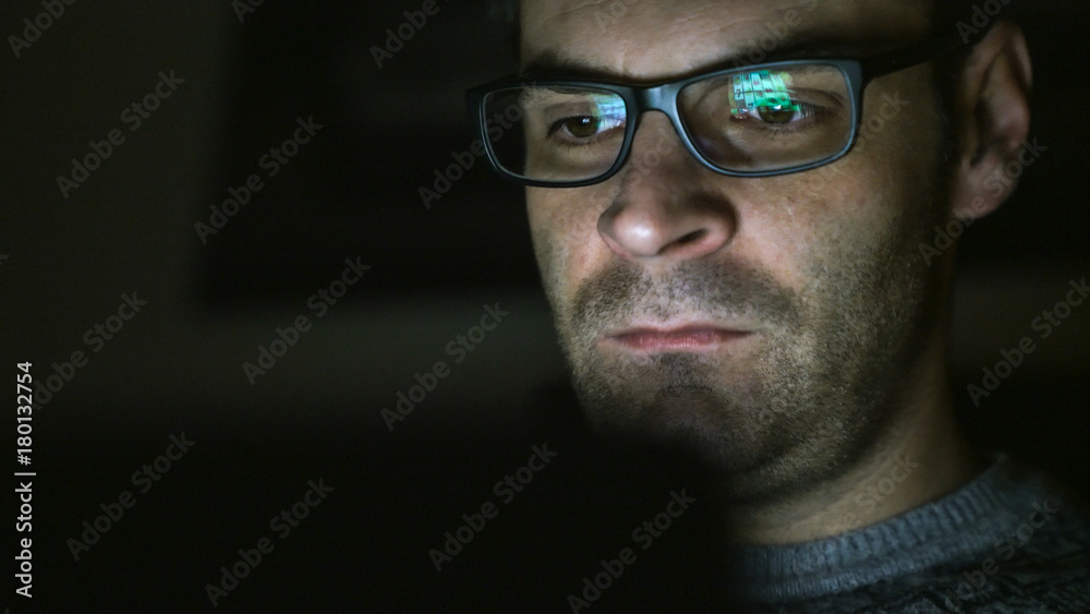 Gambling addicted man with glasses in front of online casino slot machine on laptop computer at night - loosing his money. Dramatic low light grain shot. Gambling addicted man with glasses in front of online casino slot machine on laptop computer at night - loosing his money. Dramatic low light grain shot.